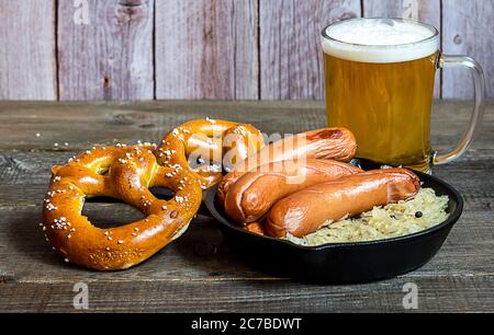 Oktoberfest traditionelle Küche. Deutsche Bratwurst mit Sauerkraut, Bier und Brezeln Stockfoto