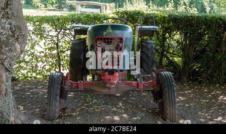 Weggeworfener Traktor unter einem Baum Stockfoto