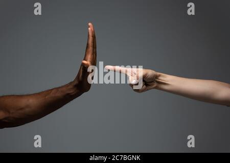 Stoppen Sie Rassismus. Rassistische Toleranz. Respektieren Sie die soziale Einheit. Afrikanische und kaukasische Hände gestikulieren auf grauem Studiohintergrund. Menschenrechte, Freundschaft, Konzept der Einheit der Intenationalen. Interrassische Einheit. Stockfoto