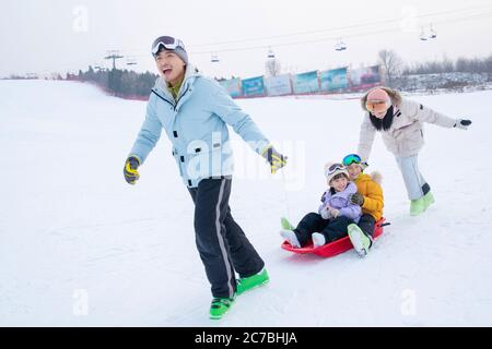 Spielen Schnee Skateboard Glück einer Familie von vier Stockfoto