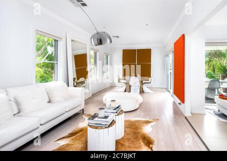 Innenaufnahme eines modernen Wohnzimmers mit Sofas im Vordergrund, Tisch und Gemälden im Hintergrund Stockfoto