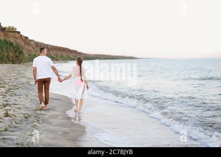 Das junge Paar geht an der Küste entlang. Rückansicht Stockfoto