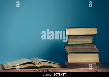 Schöne offene Bücher auf einem alten roten Holztisch und blauen Wandhintergrund. Stockfoto