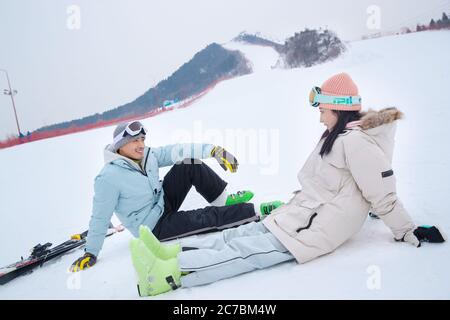 Fröhlicher junger Begleiter saß im Schnee plaudernd Stockfoto