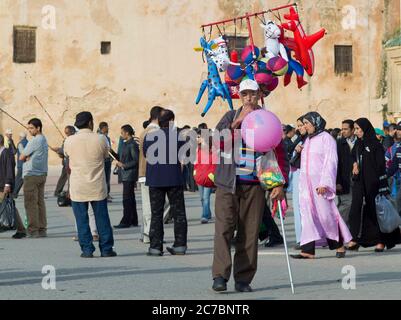 Mann, der am Nachmittag auf dem Platz in der Nähe der Stadtmauer in Meknes, Marokko, Ballons verkauft Stockfoto