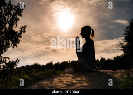 Entspannte Dame ist Durchführung namaste Yoga Pose Hintergrund der Sonne im Freien auf Park außerhalb der Stadt Abend. Stockfoto