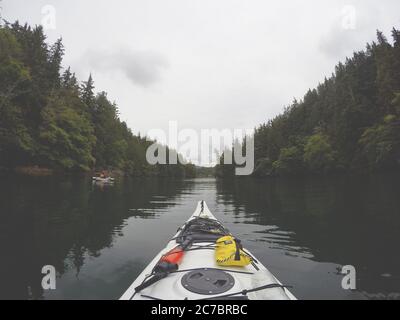 Horizontale Aufnahme von einem Kajak, das durch ein Gewässer in Bamfield, Vancouver Island, Kanada segelt Stockfoto