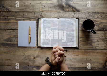 Overhead Aufnahme der männlichen Hand in der Nähe eines offenen Buches und Kaffeetasse auf einer Holzoberfläche Stockfoto