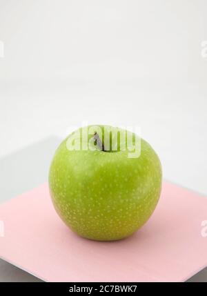 Reifer grüner Apfel auf einem rosa-grauen Hintergrund Stockfoto