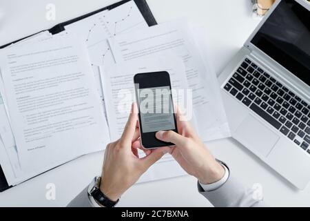 Oben Ansicht von unkenntlichen Anwalt mit Smartphone beim Fotografieren von Vertragsunterlagen auf dem Tisch Stockfoto