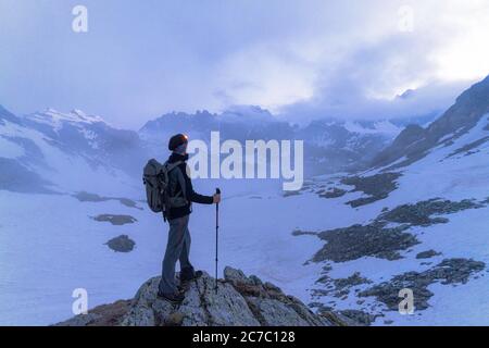 Wanderer auf Felsen in Bocchetta delle Forbici bewundern die Alpen bei Sonnenaufgang, Valmalenco, Valtellina, Lombardei, Italien Stockfoto