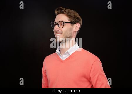 Lächelnd zuversichtlich gut aussehende junge bärtige Kerl in Brillen Blick neben vor schwarzem Hintergrund, Zweck Konzept Stockfoto