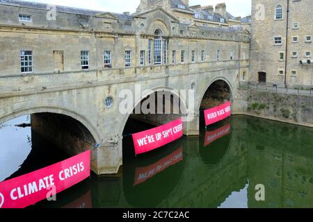 Bath, 16. Juli 2020. Die Demonstranten des Klimawandels Aussterben Rebellion hat unter den Bögen der historischen Pulteney-Brücke am Fluss Avon in Bath Banner angebracht. Die Botschaft ist, dass wir nach der Corona Virus Pandemie in einer grünen Weise, die für die Umwelt sympathisch ist, wieder aufbauen sollten. Kredit: JMF Nachrichten/Alamy Live Nachrichten Stockfoto