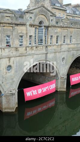 Bath, 16. Juli 2020. Die Demonstranten des Klimawandels Aussterben Rebellion hat unter den Bögen der historischen Pulteney-Brücke am Fluss Avon in Bath Banner angebracht. Die Botschaft ist, dass wir nach der Corona Virus Pandemie in einer grünen Weise, die für die Umwelt sympathisch ist, wieder aufbauen sollten. Kredit: JMF Nachrichten/Alamy Live Nachrichten Stockfoto