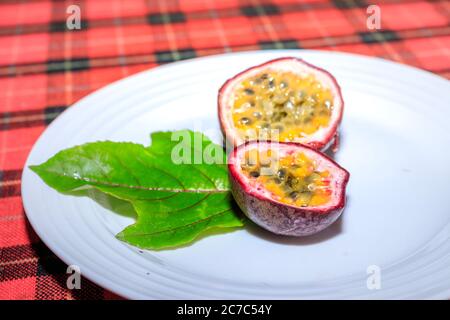 Passionsfrucht (Passiflora edulis) Frucht auf weißem Tischteller, Uganda, Afrika Stockfoto