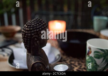 Fokussierte Aufnahme der Buddha-Statue Kopf auf dem Tisch mit Ein traditioneller asiatischer Tee im Hintergrund Stockfoto