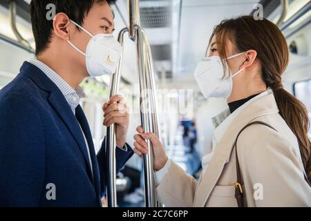 Tragen Sie eine Maske der jungen Paare nehmen Sie die U-Bahn Stockfoto