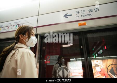 Die junge Frau stand in einer Maske auf dem U-Bahnsteig Stockfoto