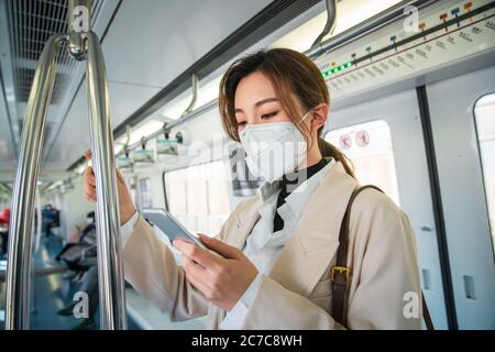 Die junge Frau in der U-Bahn schaut auf das Handy Stockfoto