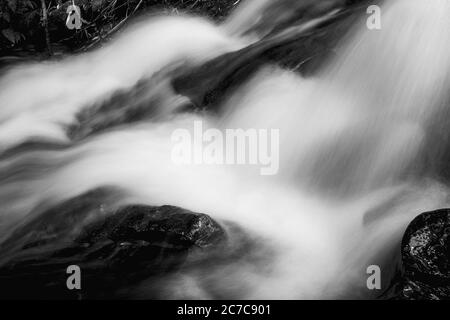 Nahaufnahme eines schaumigen Wasserfalls, der durch Felsen fließt Stockfoto