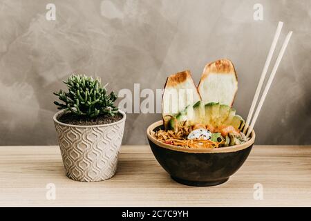 Nahaufnahme einer Schüssel voller Nahrung und ein Pflanze den Topf auf einen Holztisch Stockfoto