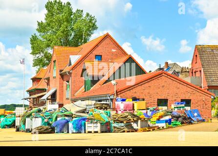 Ein sehr kleiner und winziger Hafen in Maasholm, Deutschland, mit einem Huddle traditioneller Fischfangausrüstung vor einem roten Haus Stockfoto