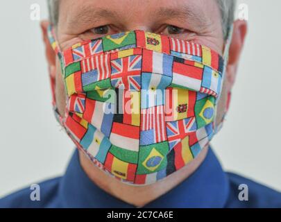 Wildau, Deutschland. Juli 2020. Ein Mann trägt einen selbstgenähten Mund-Nase-Protektor, der mit verschiedenen Flaggen von Ländern gestaltet ist. Quelle: Patrick Pleul/dpa-Zentralbild/ZB/dpa/Alamy Live News Stockfoto