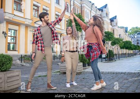 Guy und zwei Mädchen stehen in identischen Posen auf der Straße. Stockfoto