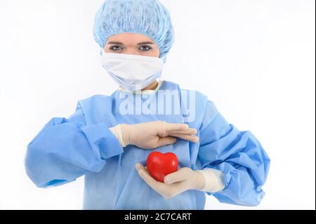 Krankenschwester oder Ärztin in steril blauem Gewand und Handschuhen, die das Herz in schützender Position halten Stockfoto