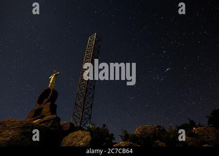 Low-Angle-Aufnahme eines metallischen Turms und einer Statue Auf einem Berg unter einer sternenklaren Nacht Stockfoto