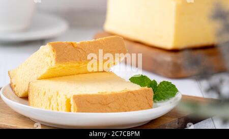 Einfache klassische taiwanesische traditionelle Biskuitkuchen (taiwanesische castella kasutera) auf einem Holztablett Hintergrund Tisch mit Zutaten, Nahaufnahme. Stockfoto