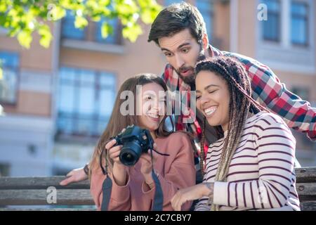 Mit Spaß Grimacing Kerl und zwei Mädchen mit Kamera Stockfoto