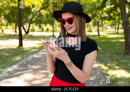 Portrait einer schönen lächelnden Frau mit Smartphone im Park Stockfoto