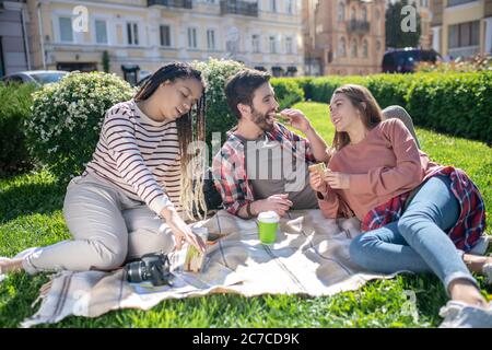 Zwei Mädchen und ein Mann essen Sandwiches auf einem Picknick Stockfoto