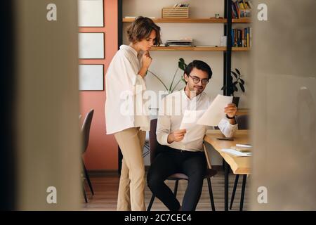 Junge attraktive Kollegen lesen bei der Arbeit im Büro nachdenklich Papiere Stockfoto