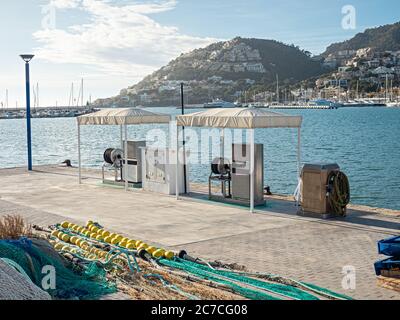 Mittag an leerer Tankstelle ohne Kunde. Fischernetz im Vordergrund. Tankstelle im Seehafen. Port d'Andratx, Mallorca Stockfoto