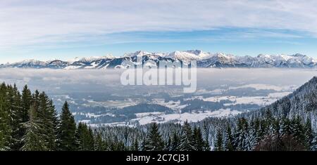 Herrlicher Panoramablick auf verschneite Berge über nebligen Wolkenschichten. Blick vom Rangiswangerhorn nach Illertal, Allgau, Bayern, Deutschland. Stockfoto