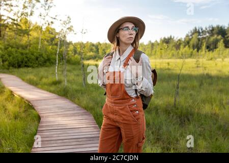 Portrait einer Botanistin mit Rucksack auf ökologischem Wanderweg im Sommer. Naturforscher erkunden Wildtiere und Ökotourismus Abenteuer Wandern auf dem Weg Stockfoto