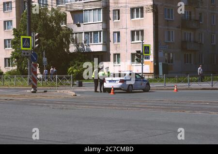 Sankt Petersburg, Russland - 12. Juni 2020: Autobahnpatrouille von drei Polizisten in medizinischen Masken neben einem Polizeiauto Stockfoto