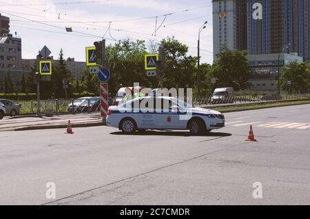 Sankt Petersburg, Russland - 12. Juni 2020: Polizeiauto blockiert die Passage auf der Straße in der Nähe von Straße Polizisten in medizinischen Masken Stockfoto