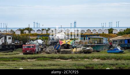 Brighton UK 16. Juli 2020 - Bunte Hausboote auf Grund im Fluss Adur bei Shoreham in der Nähe von Brighton mit der Rampion Offshore Wind Farm am Horizont an einem warmen hellen Tag in Sussex als wärmere sonnige Wetter für später in der Woche und am Wochenende in ganz Großbritannien prognostiziert : Credit Simon Dack / Alamy Live News Stockfoto