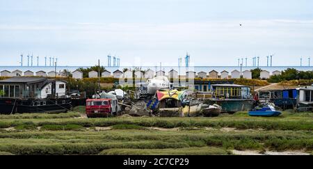 Brighton UK 16. Juli 2020 - Bunte Hausboote auf Grund im Fluss Adur bei Shoreham in der Nähe von Brighton mit der Rampion Offshore Wind Farm am Horizont an einem warmen hellen Tag in Sussex als wärmere sonnige Wetter für später in der Woche und am Wochenende in ganz Großbritannien prognostiziert : Credit Simon Dack / Alamy Live News Stockfoto