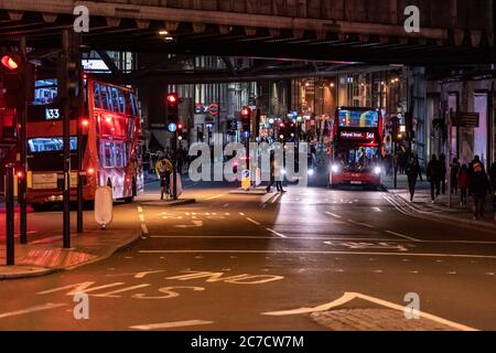 London, Großbritannien - Januar 03 2020: Ein Stadtbild von London während der Nacht. Leute und rote Busse in einem belebten Fußgängerüberweg Stockfoto