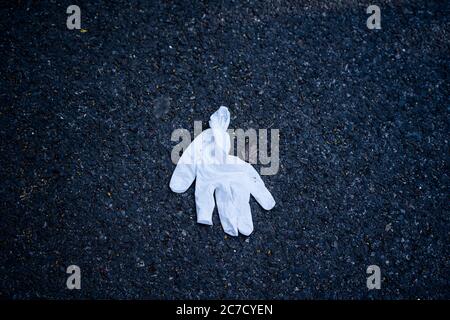 Gebrauchte weiße Gummihandschuhe auf dem Boden übersät. Die Leute haben ihre Handschuhe übersättert. Coronavirus-Pandemie Stockfoto