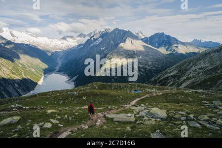 Abenteuerlicher Mann am Rande einer Klippe mit Blick auf die schönen Österreich Alpen und See während eines lebhaften Sommer Sonnenuntergang. Aufgenommen in Wandern zum Olperer Stockfoto