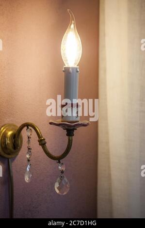 Vertikale Nahaufnahme einer eingeschaltetem Lampe auf rosa Wand am Abend Stockfoto