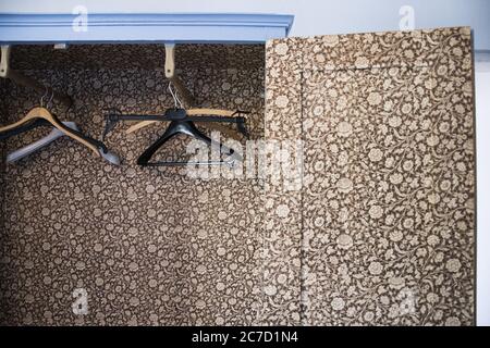 Horizontale Aufnahme von schwarzen und braunen Kleiderbügel in einem garderobe mit Blumenmuster Stockfoto
