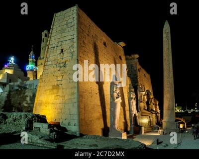 Nachts wird der Mast des luxor-Tempels mit seinen riesigen Statuen beleuchtet Stockfoto