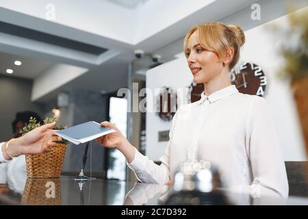 Die Dame an der Rezeption nimmt den Pass der Gäste mit zum Einchecken Stockfoto