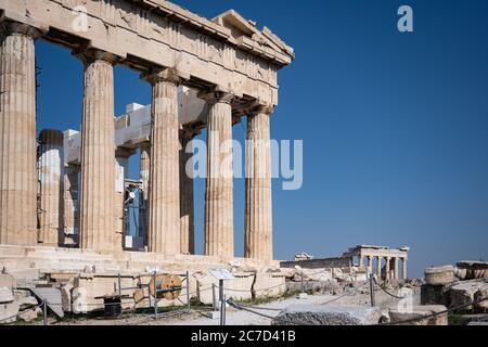 Der Parthenon und das Erechtheion der Akropolis in Athen Griechenland scheint in der warmen Sonne vor einem blauen Himmel und niemand ist anwesend. Stockfoto